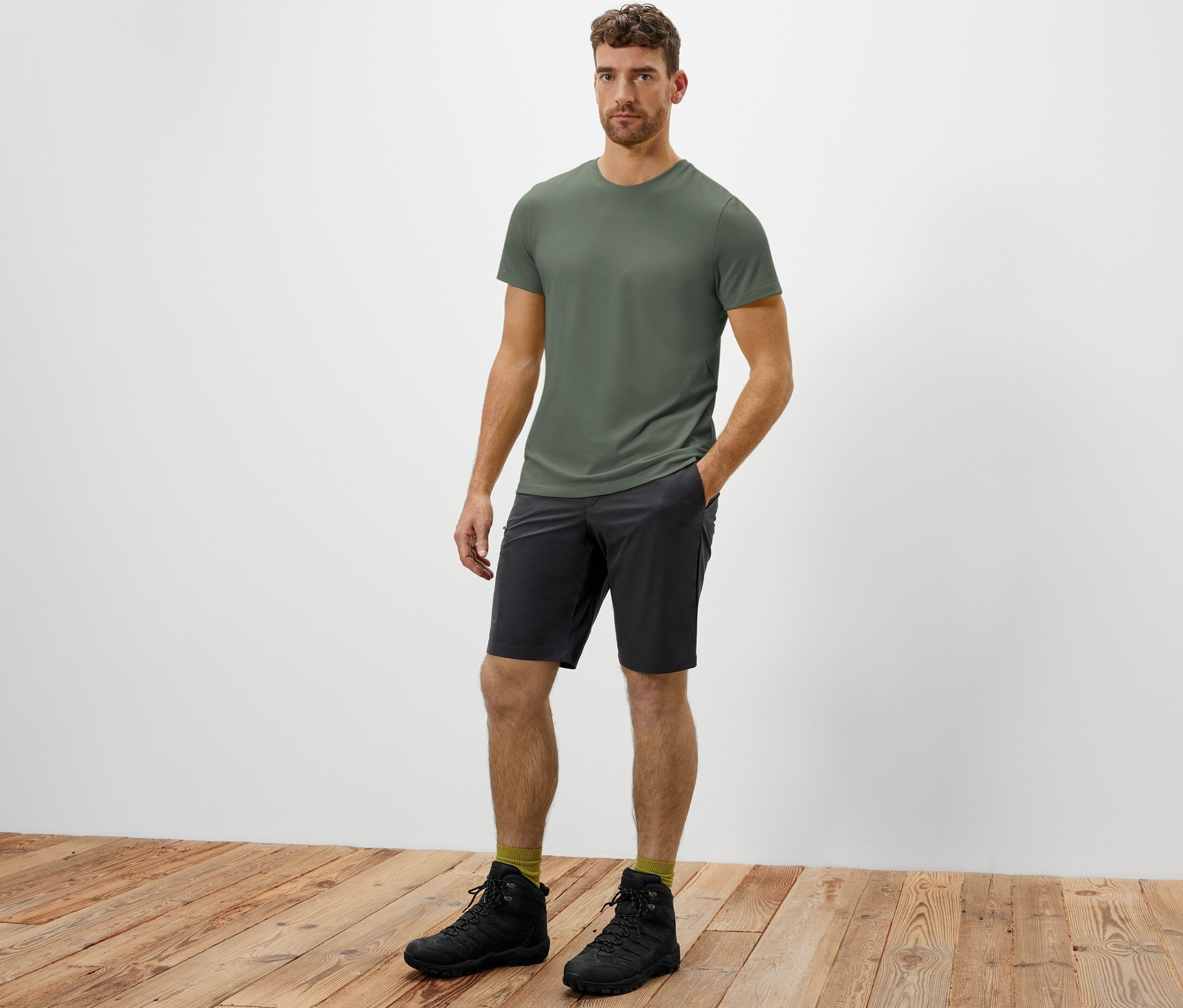 Muž stojí a má ruku v kapse softshellových funkčních šortek.