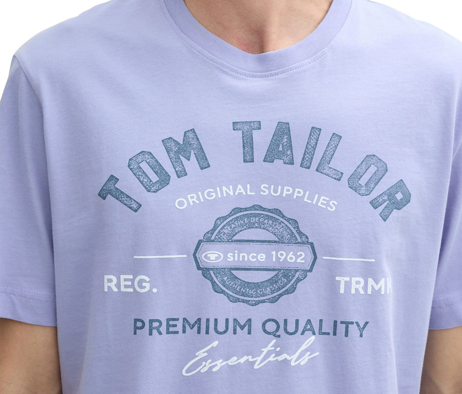 Detail muže ve světle fialovém tričku s potiskem "Tom Tailor".