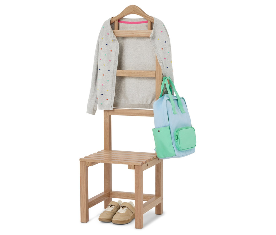 Na židli visí šedý kardigan s barevnými puntíky a světle modrá a zelená taška. Pod židlí jsou béžové boty.