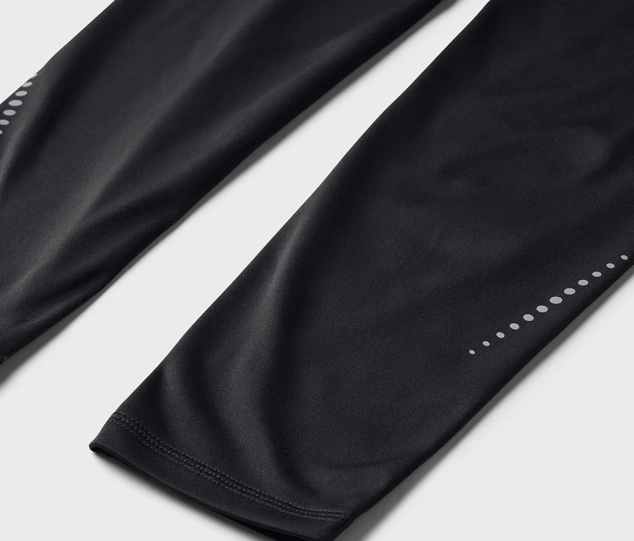 Detailní záběr černých legín s reflexními body na spodní části nohavic.