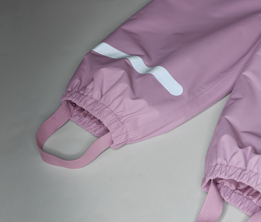 Detail růžových nepromokavých kalhot s elastickými popruhy a reflexními pruhy na nohavicích.