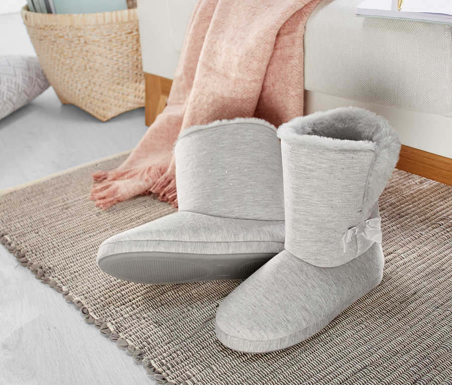 Na rohožce stojí pár vysokých domácích papučí.