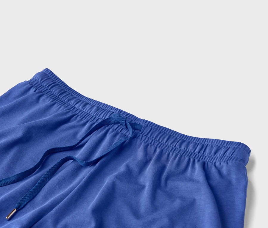 Detailní záběr na pas modrých kalhot se stahovací šňůrkou.