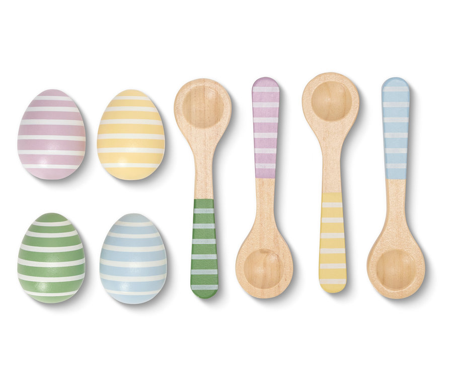 Detailní záběr na pruhovaná velikonoční vajíčka a barevně sladěné dřevěné lžíce na bílém pozadí.