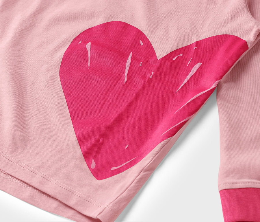 Detail růžové látky s velkým, růžovým potiskem srdce.