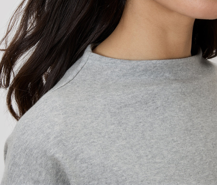 Detailní záběr ženy v šedém topu s rolákem.