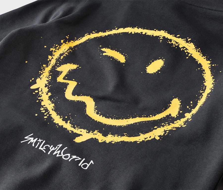 Detail černé mikiny s velkým, žlutým, opotřebovaným smajlíkem a bílým nápisem „SMILEYWORLD“ pod ním.