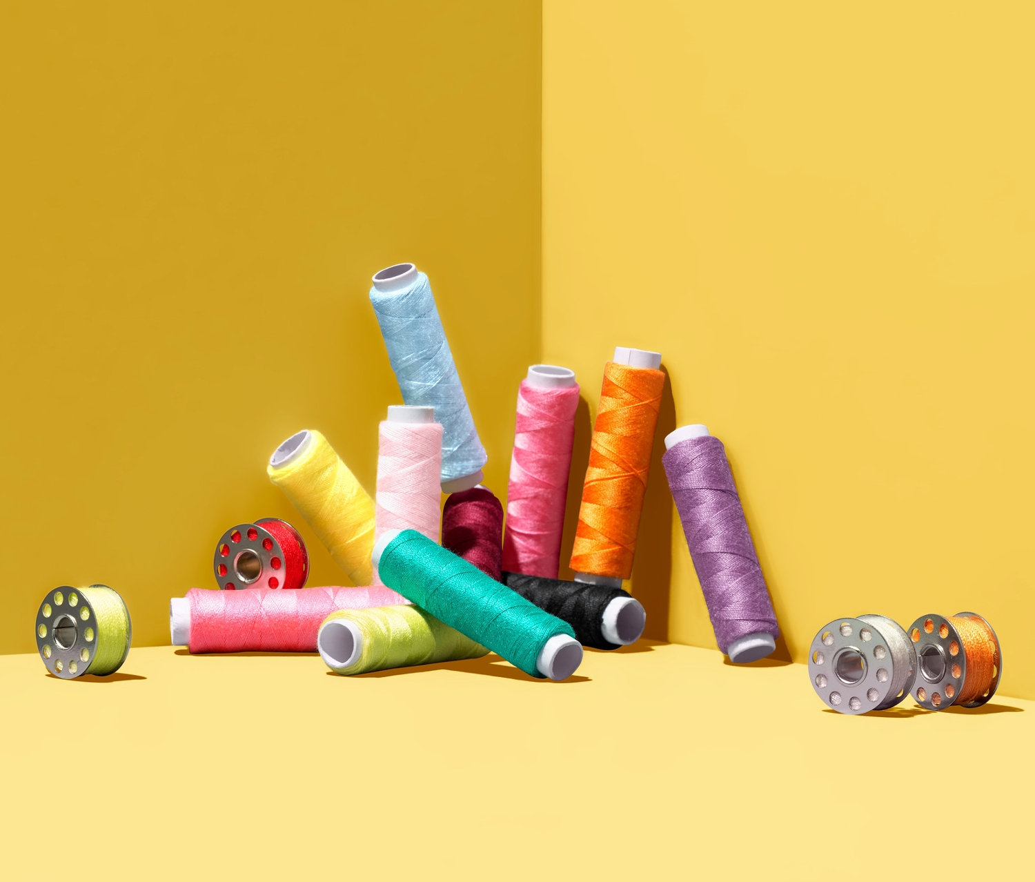 Sada šicích nití různých barev leží na žlutém pozadí.