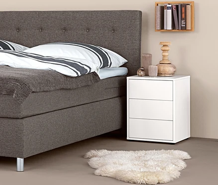 Boxspringová postel s nočním stolkem boxspring a dekoracemi.