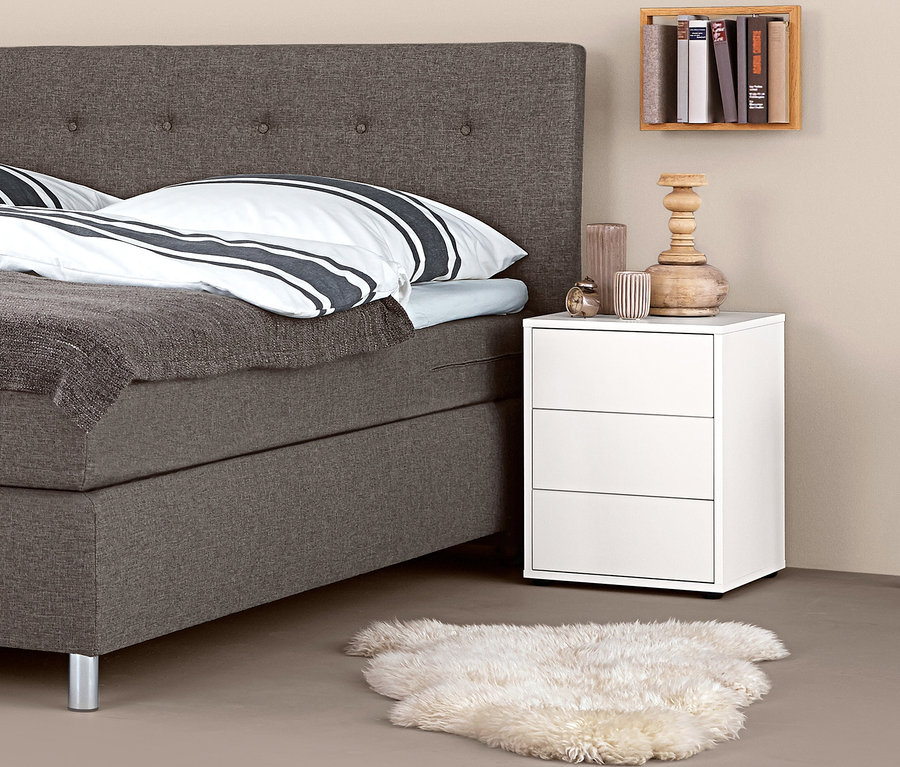 Boxspringová postel s nočním stolkem boxspring a dekoracemi.