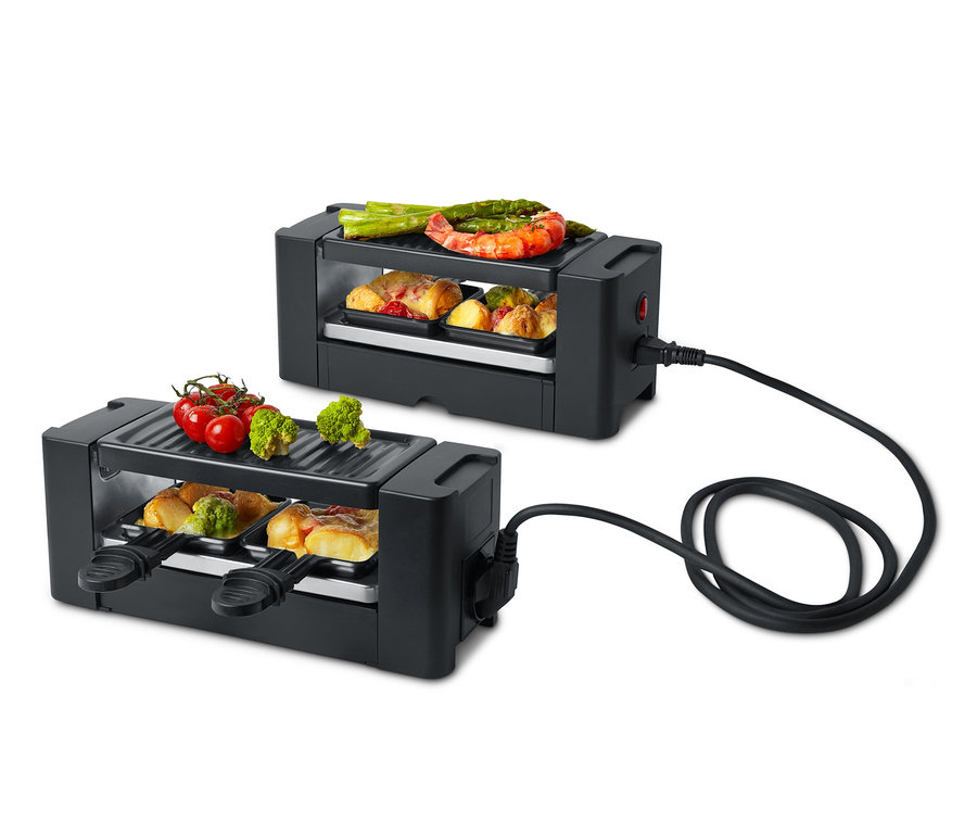 Dva černé raclette grily pro dvě osoby s různými potravinami nahoře a uvnitř.