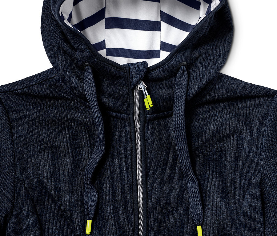 Detail modré bundy z pleteného fleecu s kapucí a zipem.