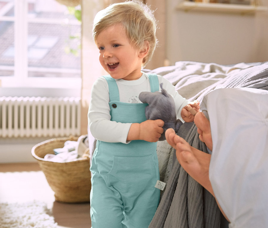 Chlapeček v bavlněných kalhotách s laclem drží plyšového slona.