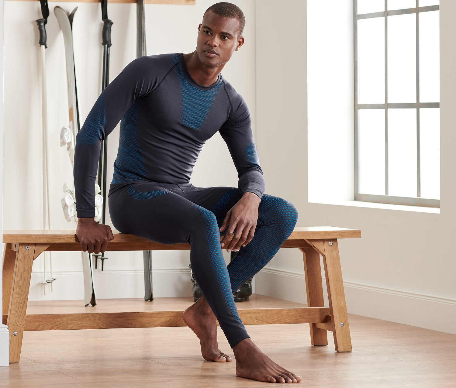 Muž sedí na lavičce a má na sobě bezešvé funkční spodní prádlo.