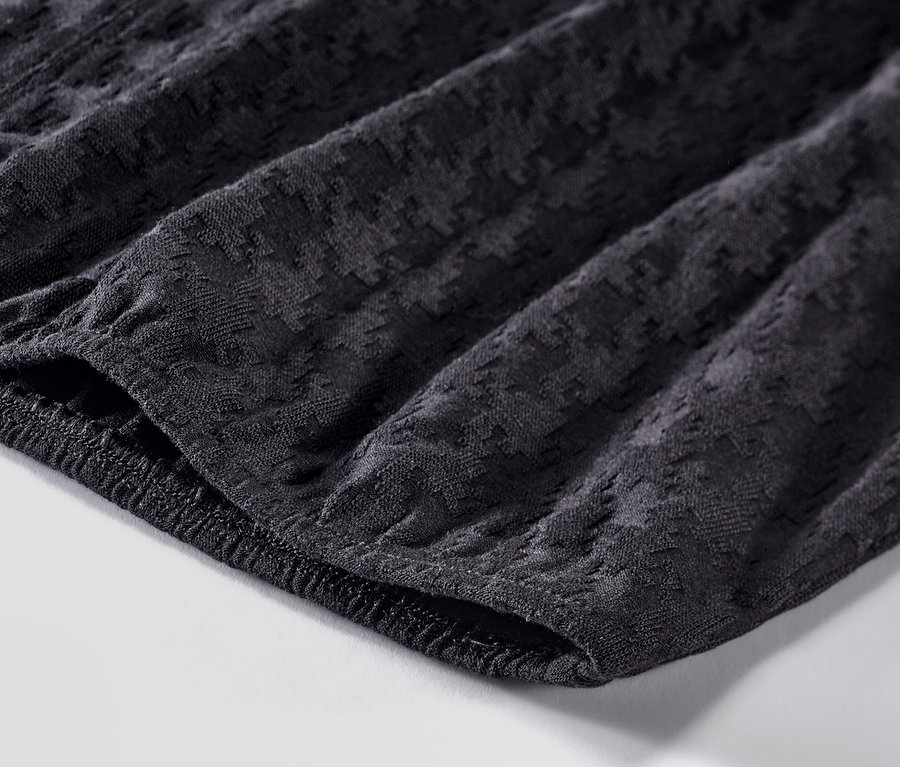 Detailní záběr na texturované černé triko s dlouhým rukávem.