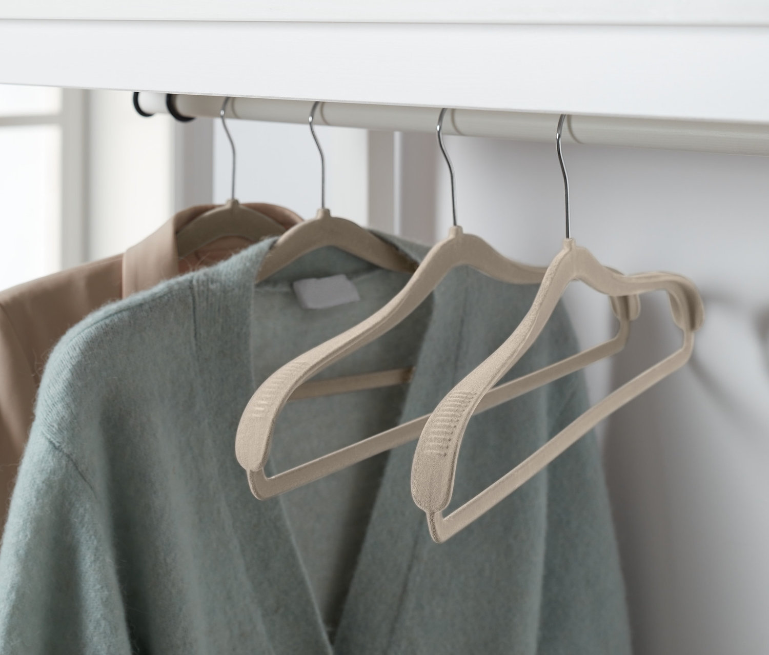 Dva svetry visí na ramínkách s výztuží, 4 ks, na bílém rámu.