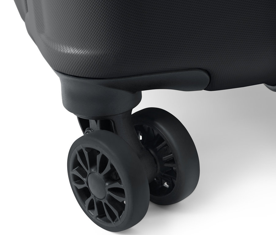 Detail velkého kufru z tvrdé skořepiny ukazující texturovaný povrch a dvě černá kolečka.