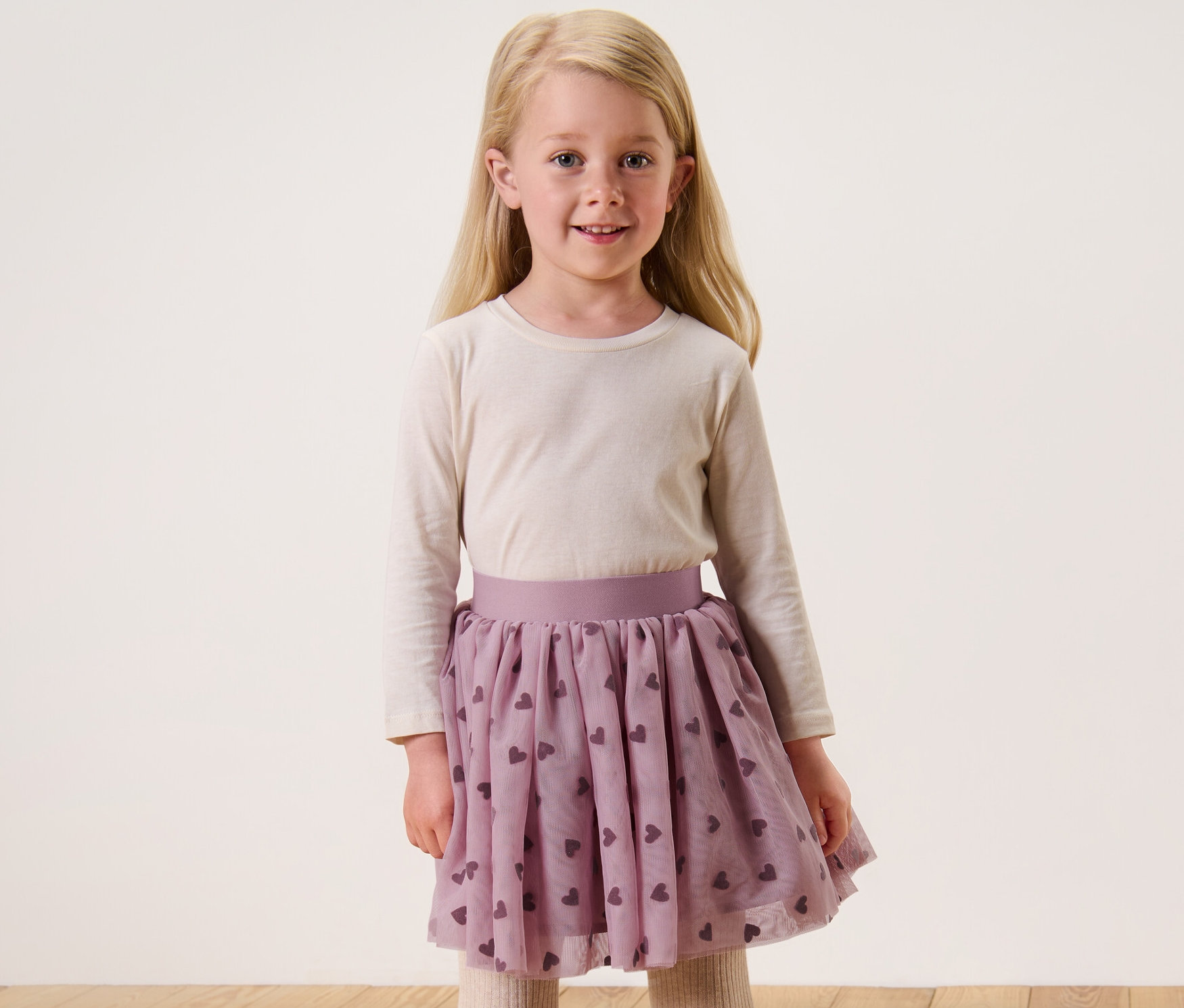 Usmívající se blondýna v dívčí tylové sukni s potiskem srdíček.