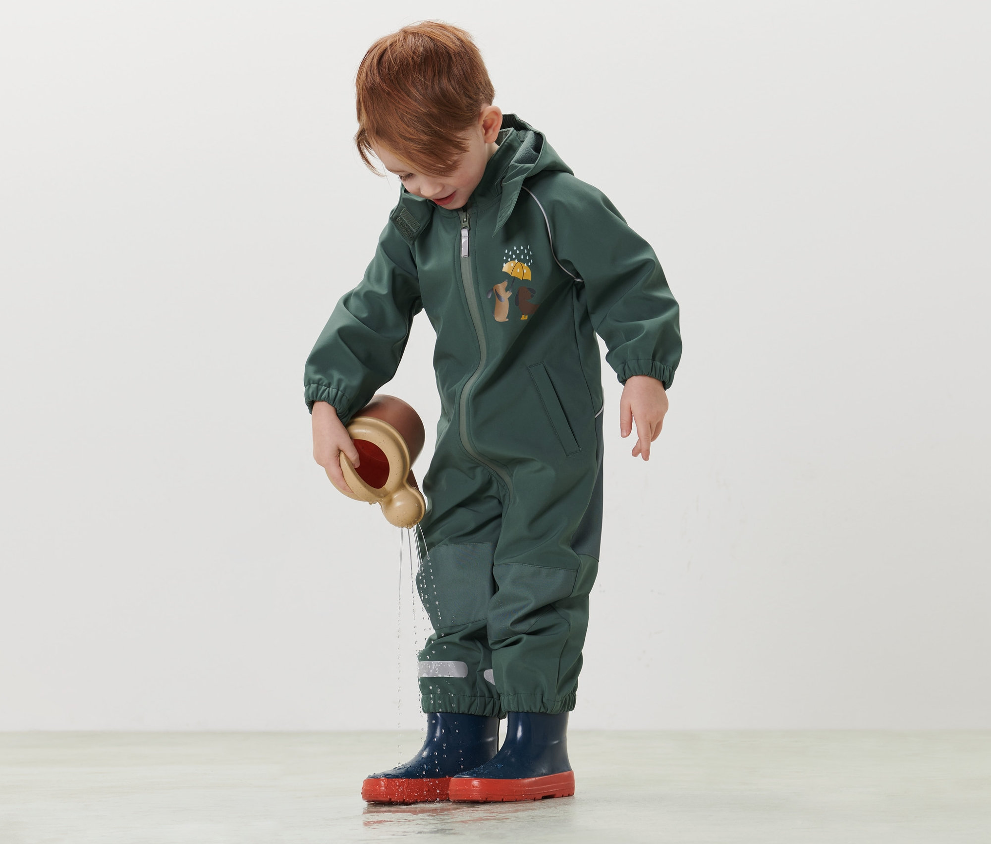 Chlapec v dětském softshellovém overalu si hraje s hračkou na vodu.
