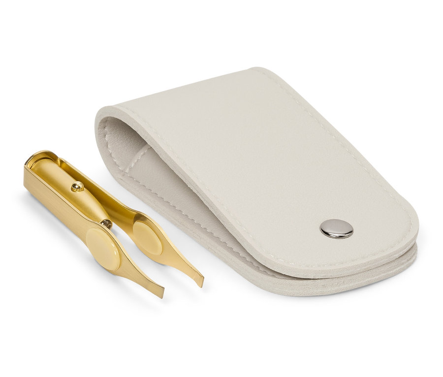 Zlatá pinzeta leží vedle otevřeného bílého pouzdra.