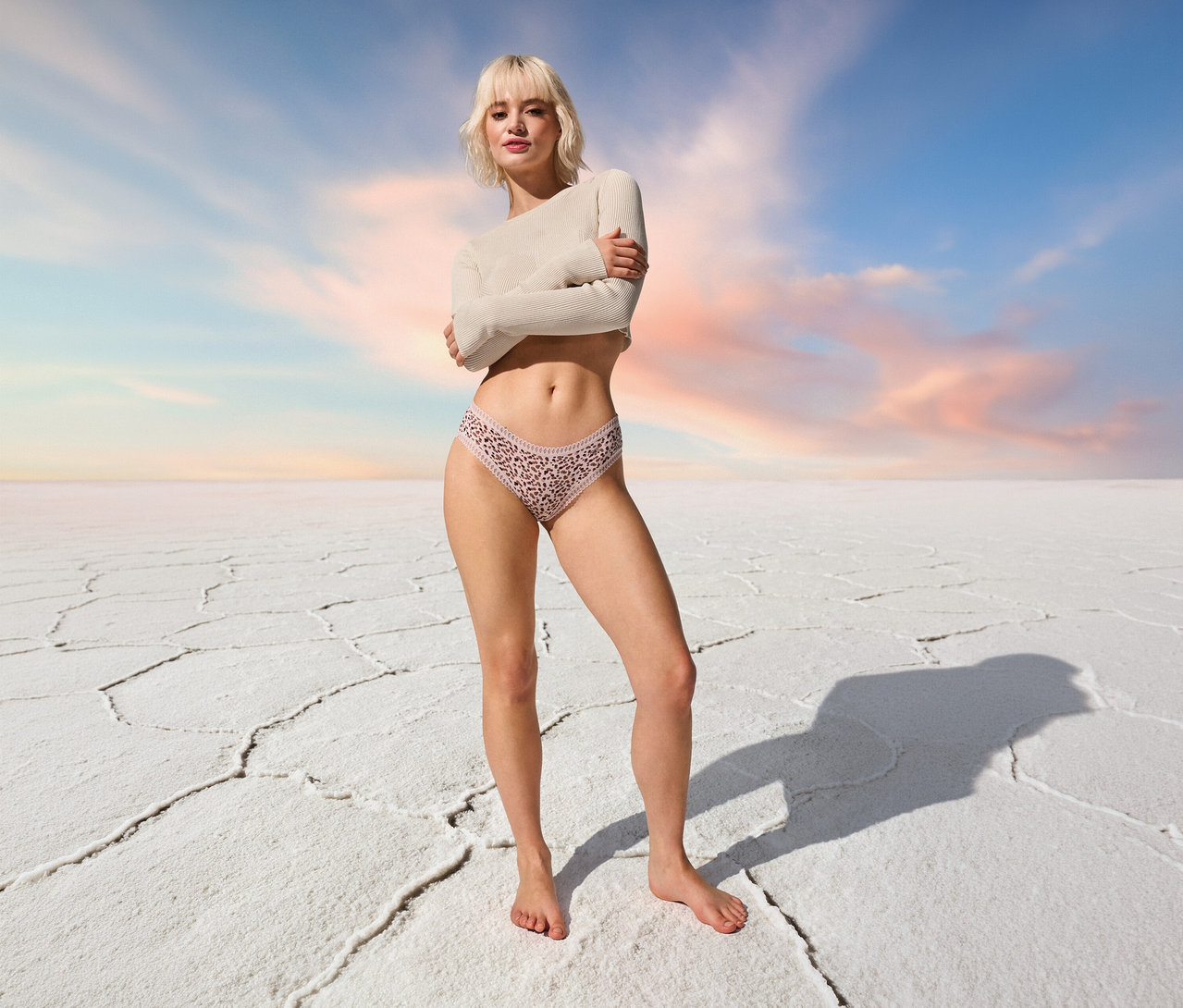 Žena stojí bosa v bokových kalhotkách sloggi GO Crush Hipster C3P, multi col. 1 před modrou oblohou.