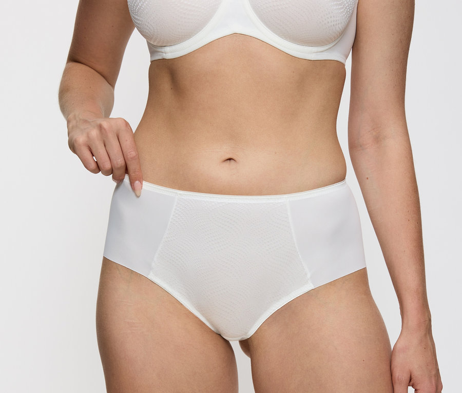 Žena má na sobě vanilkové kalhotky Triumph Essential »Minimizer Hipster X«.