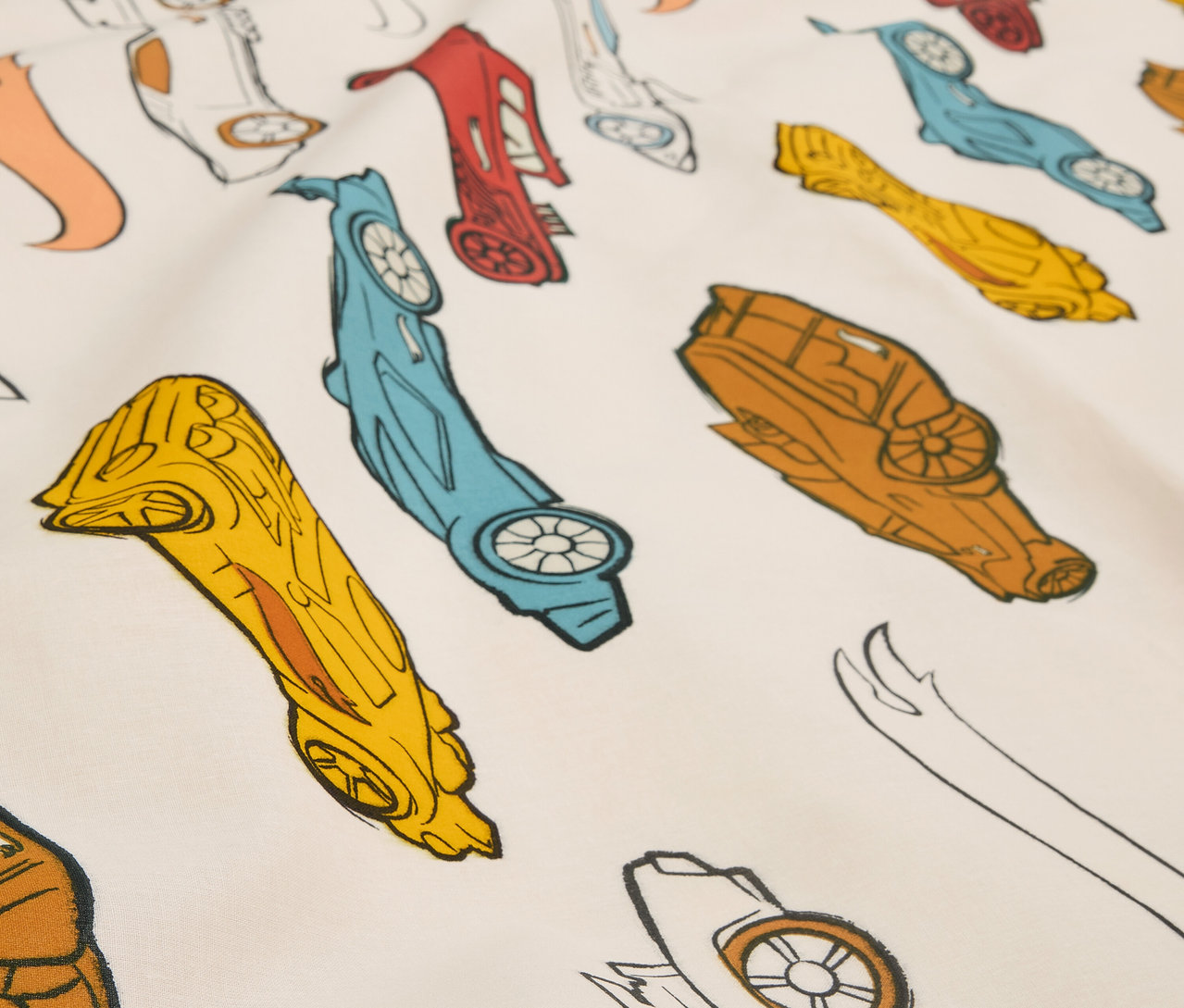 Detailní záběr na látku s potiskem stylizovaných závodních autíček v různých barvách.