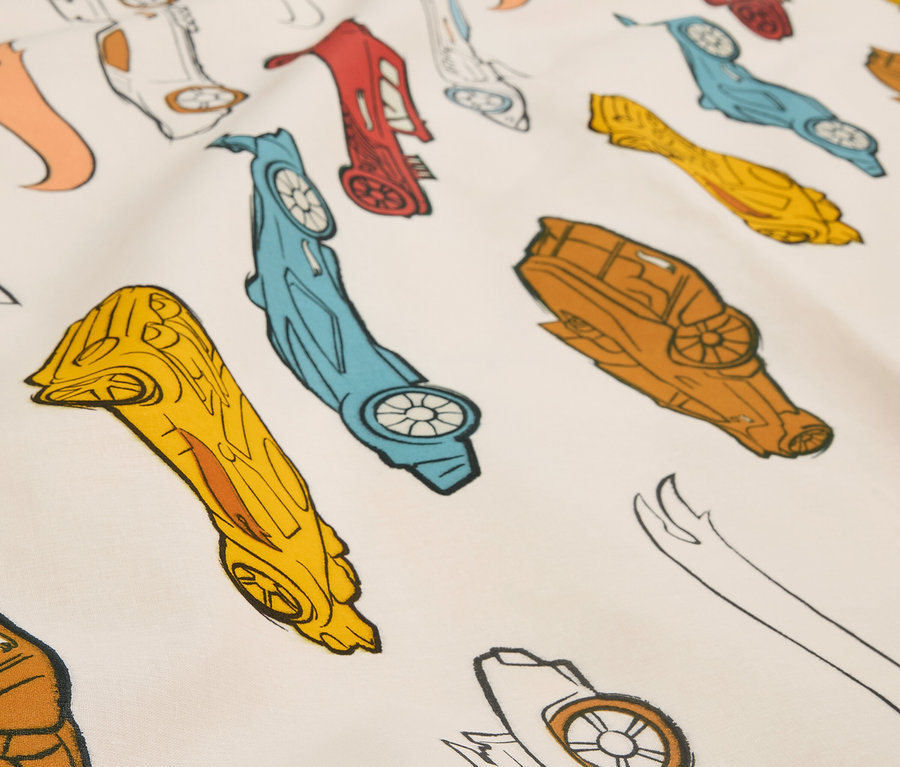 Detailní záběr na látku s potiskem stylizovaných závodních autíček v různých barvách.