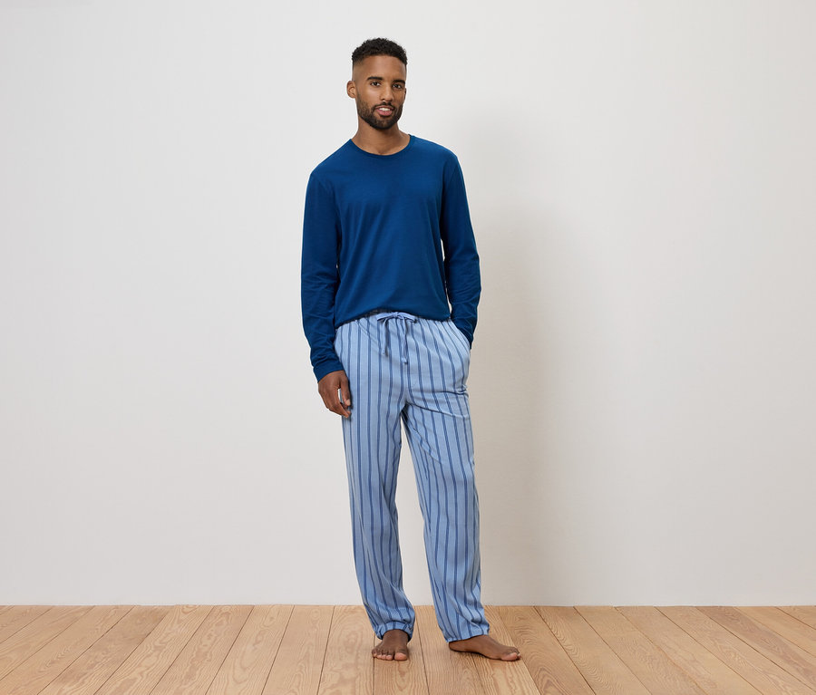Muž v modrém pyžamu s dlouhým rukávem a pruhovanými kalhotami.