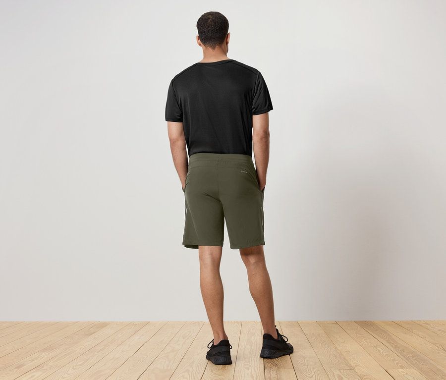 Muž zády k fotoaparátu má na sobě černé tričko a zelené šortky.