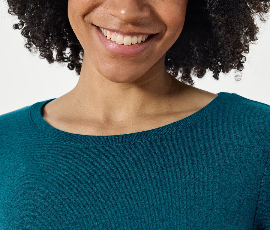 Detail usmívající se ženy s afro účesem v modrozeleném svetru.