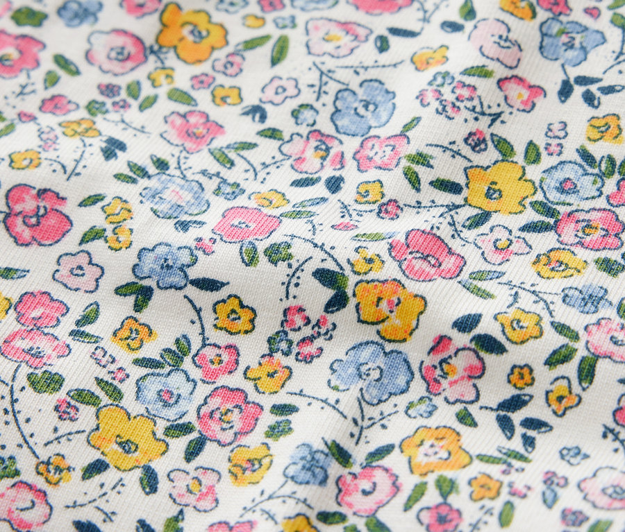 Detailní záběr na dětské legíny s květinovým vzorem v růžové, modré a žluté barvě.