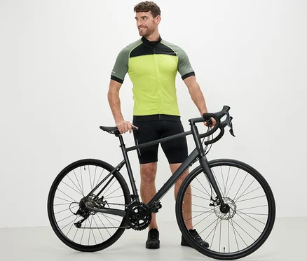 Muž stojí vedle kola a má na sobě žlutý cyklistický trikot.