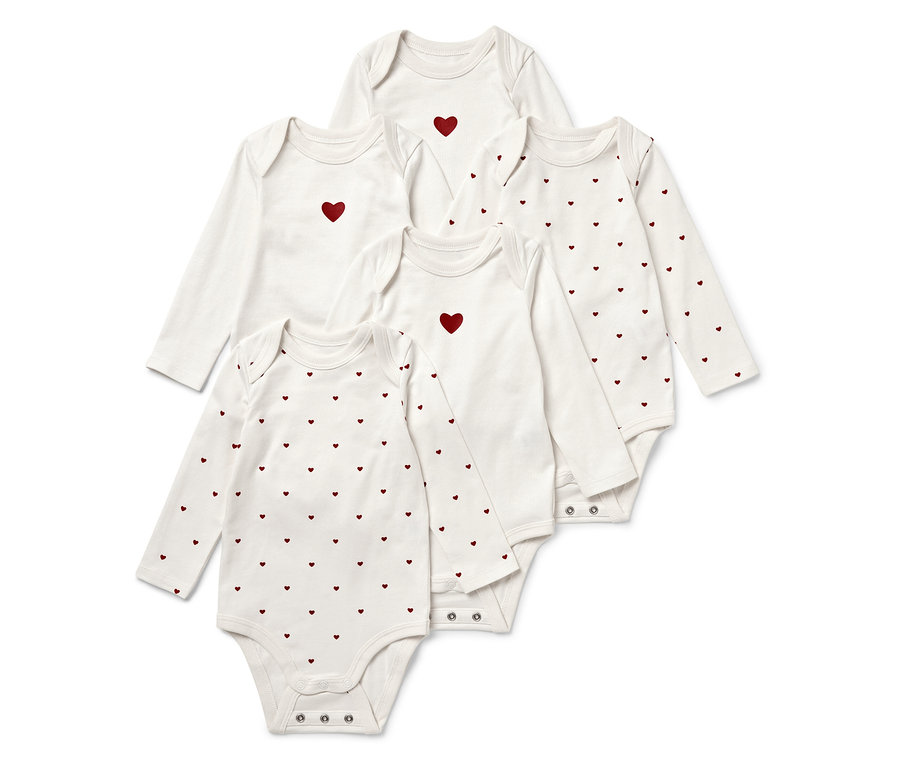 Pět bílých dětských body s dlouhým rukávem, některá s červeným srdcem uprostřed, jiná s potiskem červených srdcí.