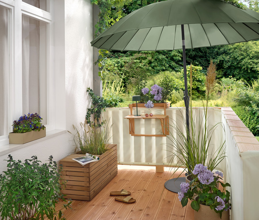 Na balkoně stojí zelený slunečník Leco Shanghai (Ø 270 cm) v plochém stojanu Leco (Ø cca 60 cm).