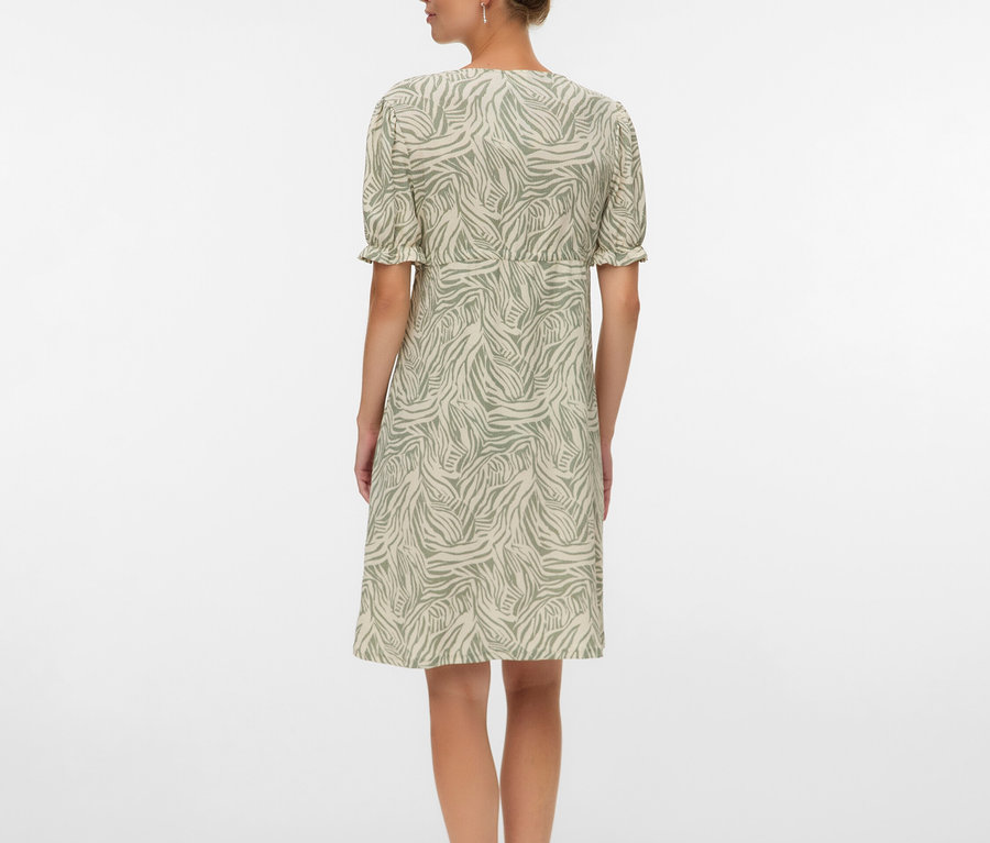 Žena zezadu v šatech ke kolenům se vzorem zebry a sandálech.