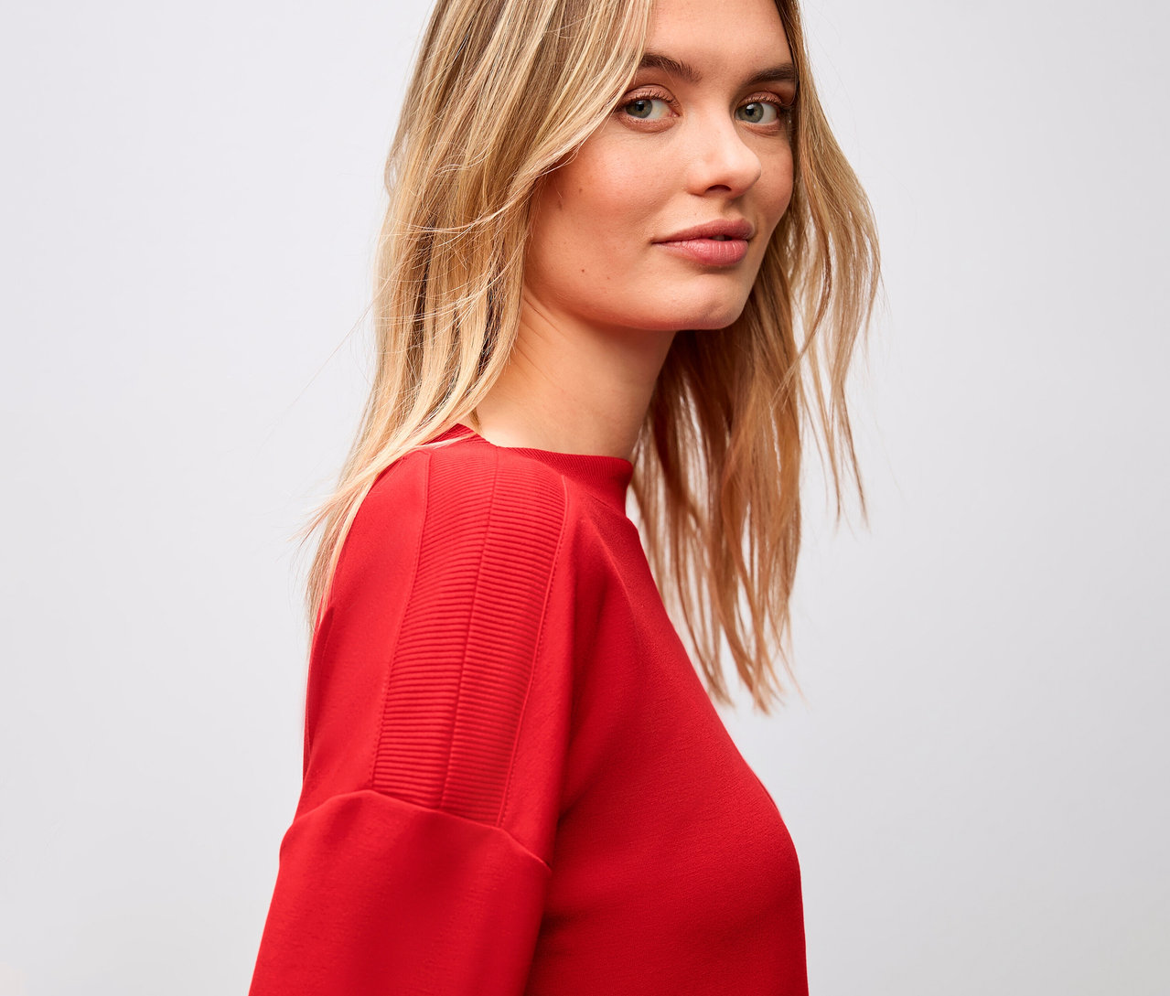 Žena má na sobě červené tričko Street One s žebrovaným detailem.