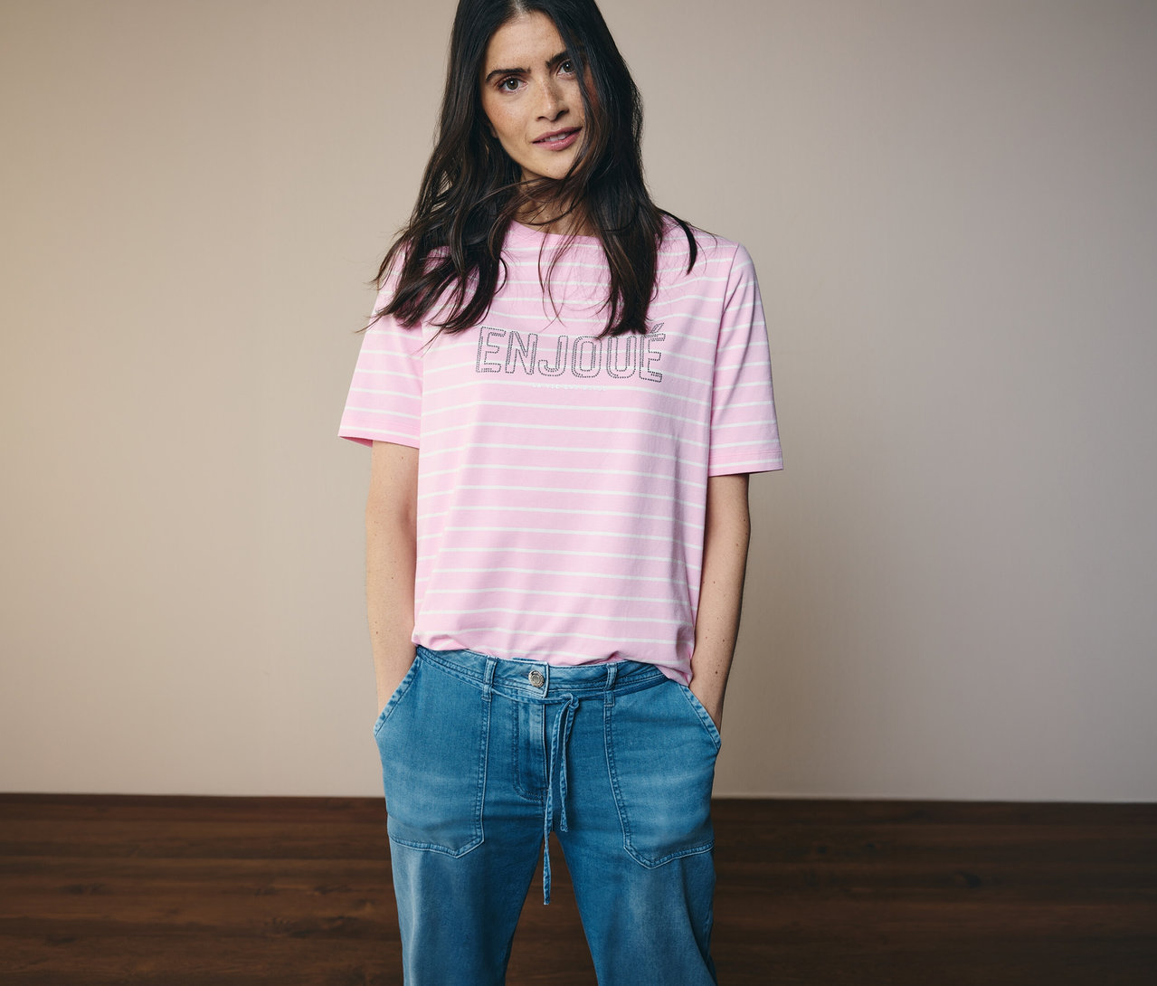 Žena v džínách a růžovo-bílém tričku CECIL s nápisem ENJOUE.