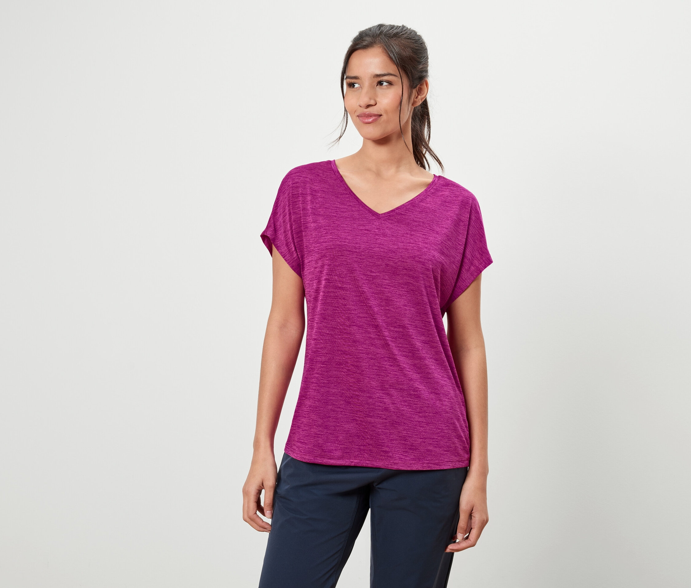 Žena má na sobě fialové tričko a modré kalhoty.