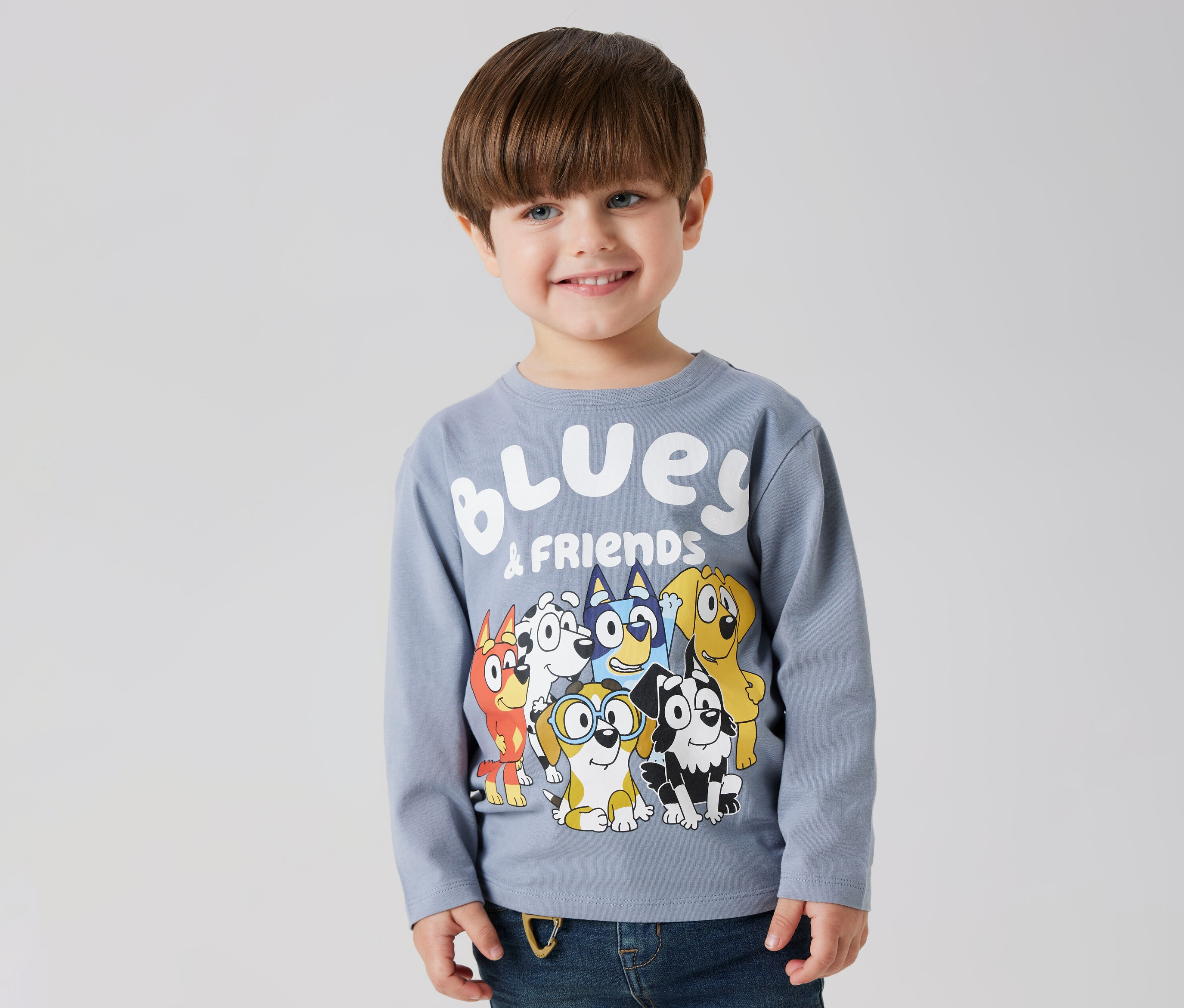 Usmívající se chlapec má na sobě dětské triko s dlouhým rukávem NAME IT »BLUEY« s motivem Bluey a přátel.