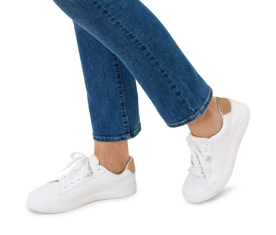 Nohy osoby v modrých džínách a bílých teniskách.