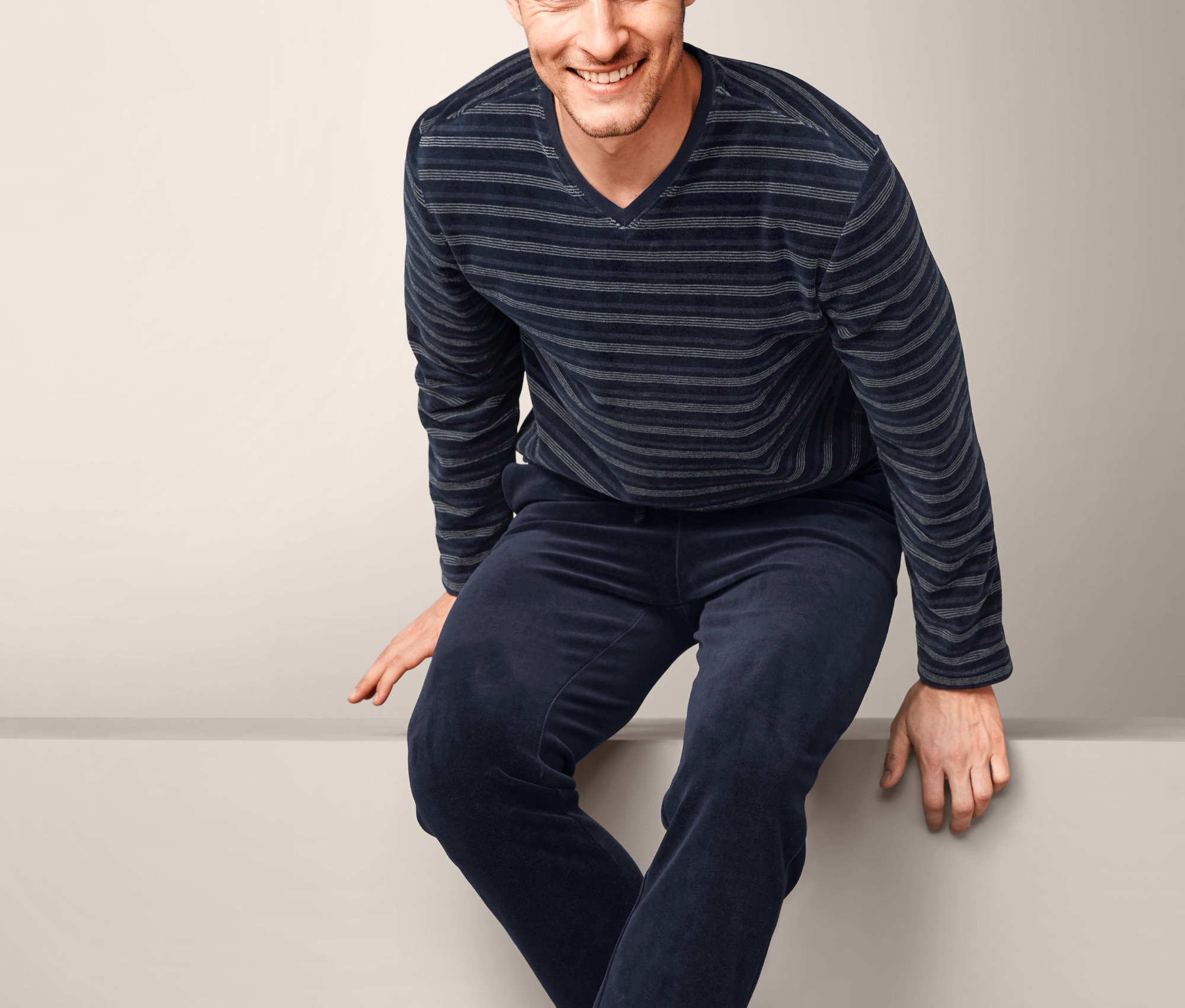 Muž sedí a má na sobě pyžamo z plyšové pleteniny.