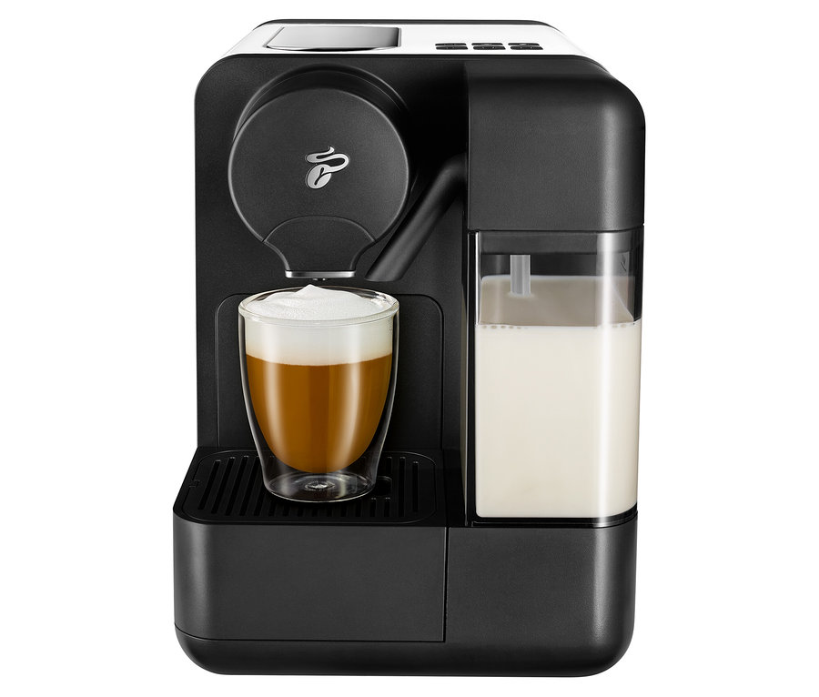 Černý kávovar s bílým mlékem Cafissimo a sklenicí naplněnou kávou.