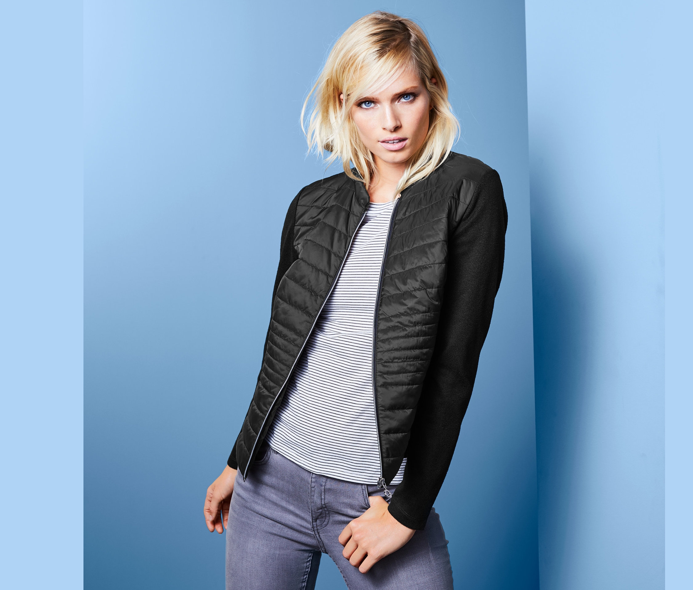 Blondýna pózuje v prošívané bundě z kombinace materiálů.