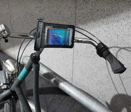 Detailní záběr na řídítka jízdního kola s držákem na smartphone.