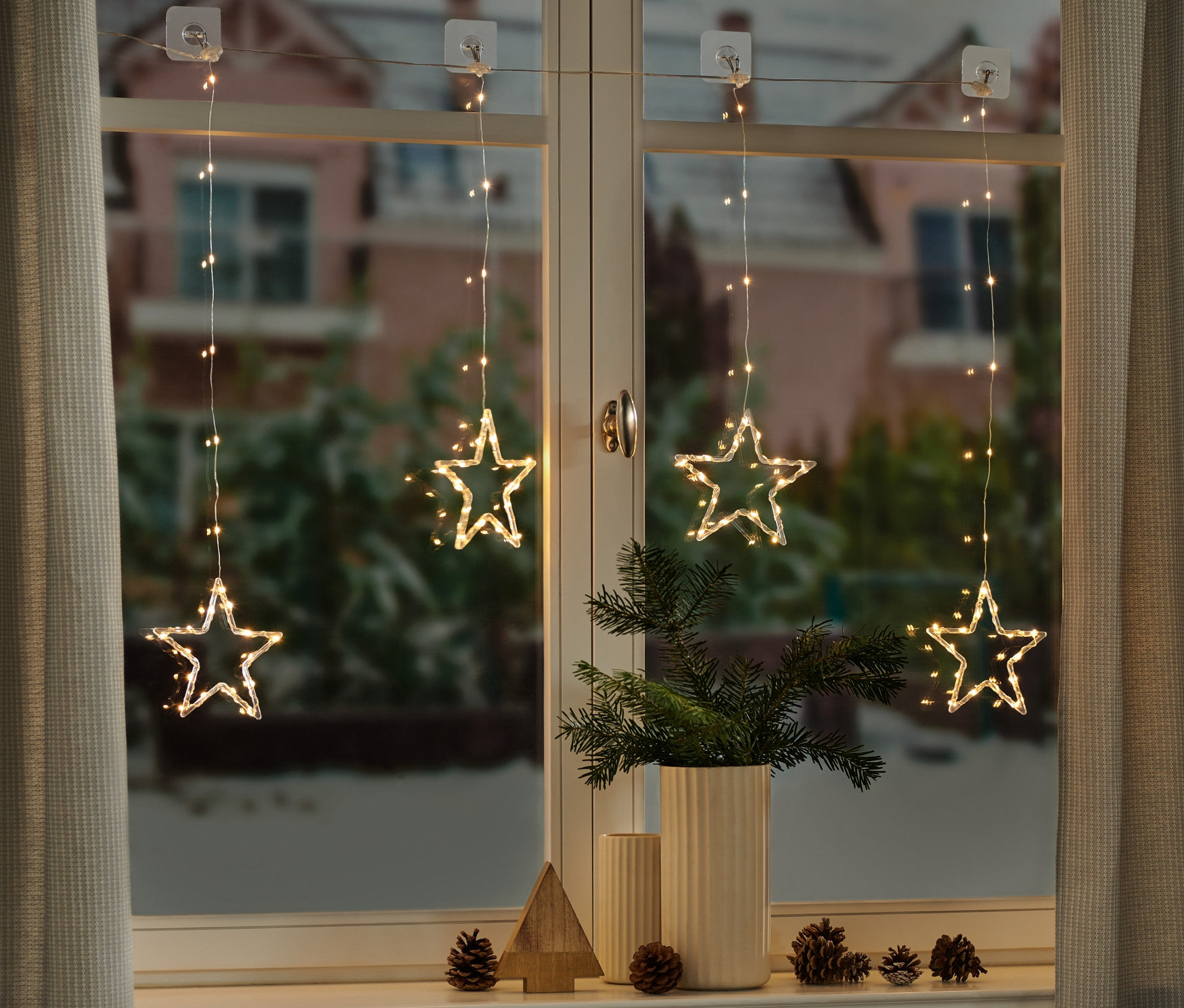 Čtyři LED světelné závěsy s hvězdami visí v okně.