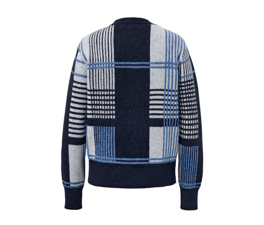 Detail kardiganu z hrubé pleteniny s modrým, bílým a černým geometrickým vzorem.