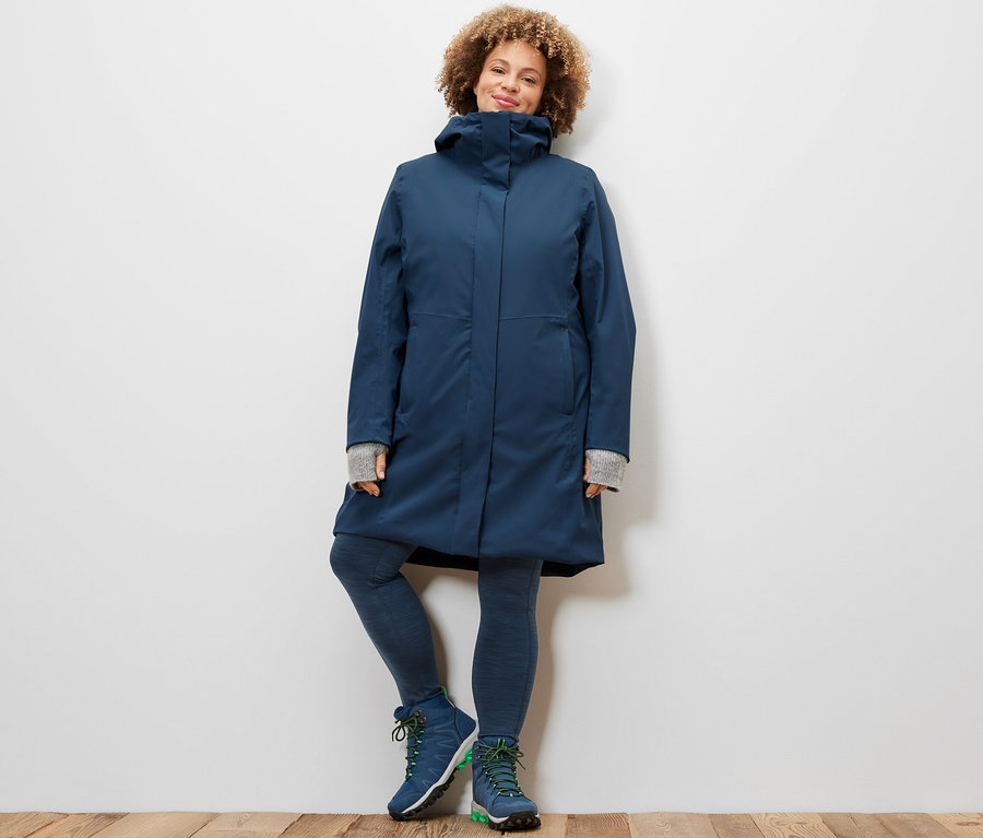 Žena pózuje ve sportovních legínách a funkčním kabátu 3 v 1.