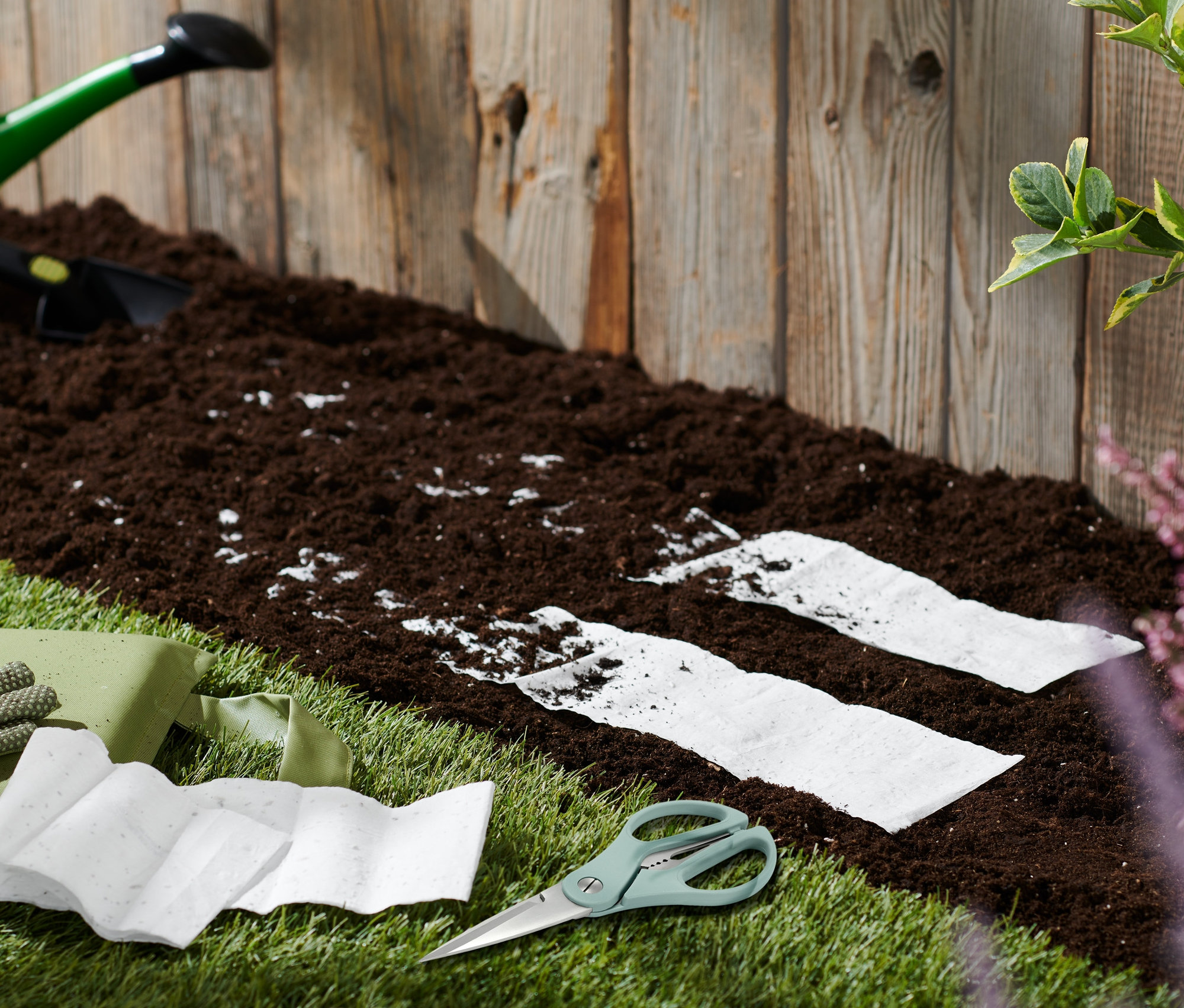 Zahradní nářadí a květinové koberce Včelí louka na trávníku u hlíny.
