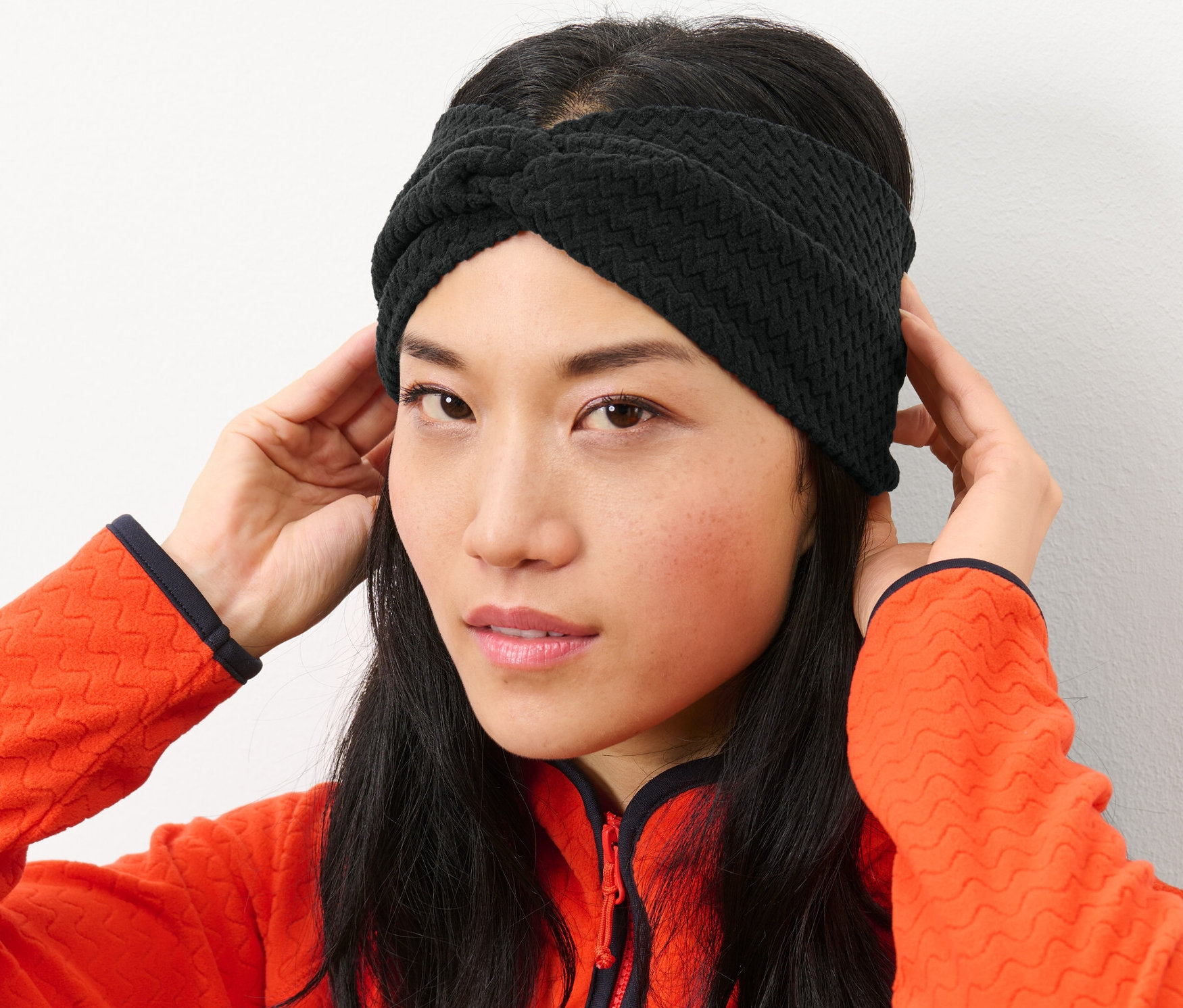 Žena si upravuje černou fleecovou čelenku.